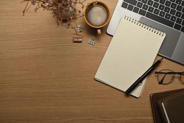 Lege notitieblok brillen pen en laptopcomputer op houten bureau Bovenaanzicht met kopieerruimte