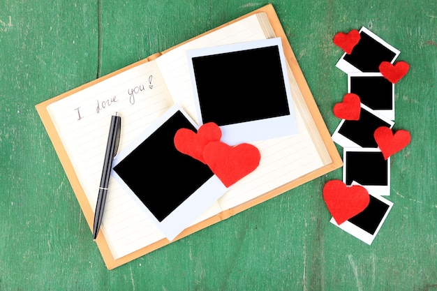 Lege oude foto's en decoratieve harten op oude notebook op een houten achtergrond kleur
