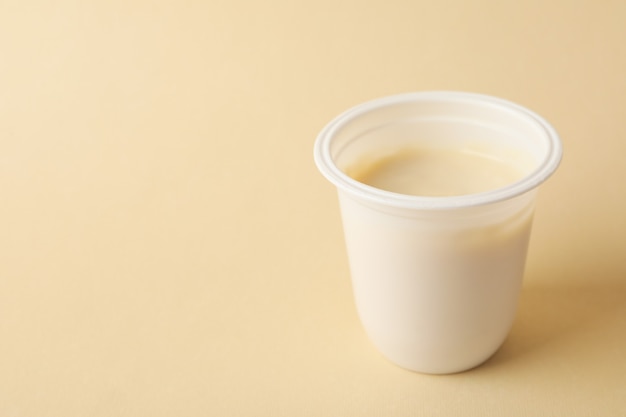 Lege plastic beker yoghurt op beige achtergrond