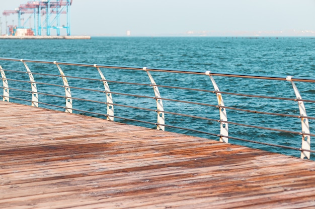 Lege promenade op een zonnige dag. metalen balustrades en houten balken van een terras langs de zee