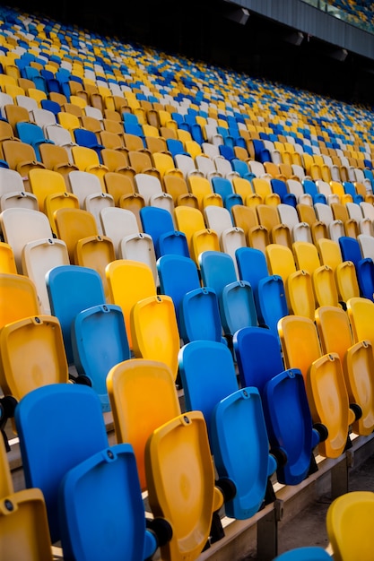 Lege rijen stoelen in een olympisch voetbalstadion met gele en blauwe banken