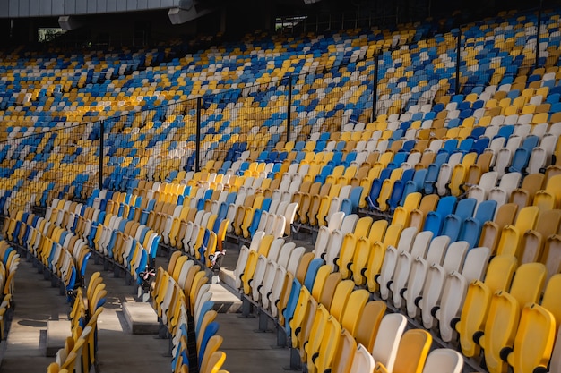 Lege rijen stoelen in een olympisch voetbalstadion met gele en blauwe banken