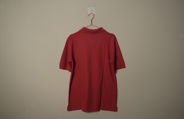 Foto lege rode casual tshirt mockup op hanger bij muur achtergrond achter zijaanzicht