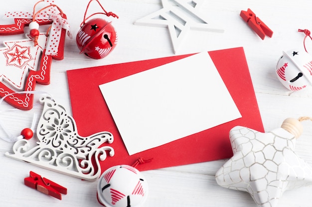 Lege rode envelop, lege nota en wit Kerstmisspeelgoed op houten rustiek