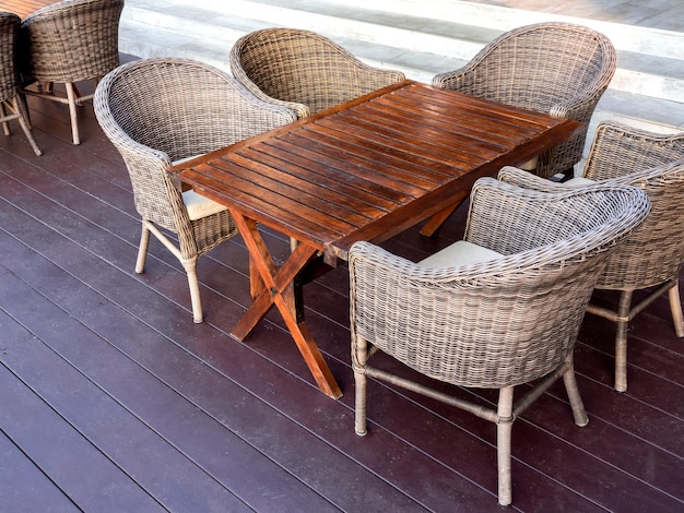 Lege rotan meubelen buiten tuin weven tafel set met houten tafel en vijf stoelen op de vloer op het terras bij de trappen in de ontbijtruimte in het resort