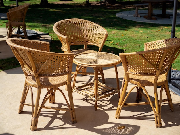 Lege rotan meubelen outdoor tuin weven tafel set met ronde tafel en drie stoelen op de groene betonnen vloer in de groene tuin eenvoudig ontwerp