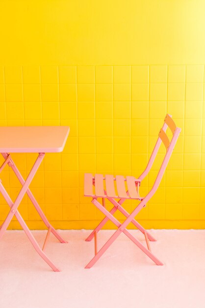 lege roze stoel en een tafel met gele muur
