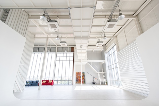 Lege schone twee verdiepingen indoor interieur industriële loft ontwerp fotografie studio workshop woonkamer in appartement vol ruimte met bankstel met kunstwerk trappen gloeilampen airconditioner systeem.