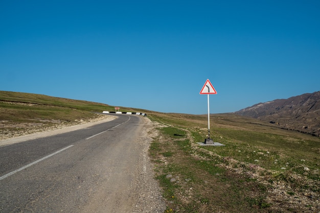 Lege snelweg door een hoog plateau. Een bordje op de weg.