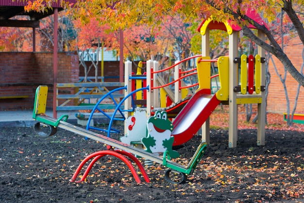 Lege speeltuin in de herfst met rood gebladerte