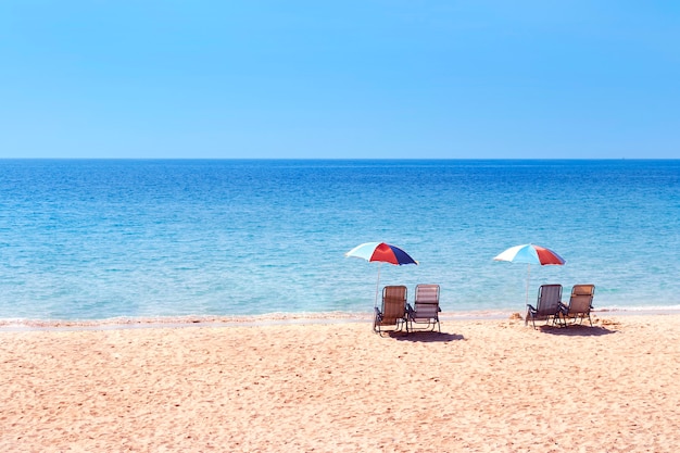 Foto lege strandstoelen op zandstrand met blauwe lucht en zee