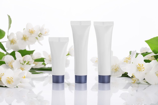 Lege tubes crème op een witte achtergrond met bloemen