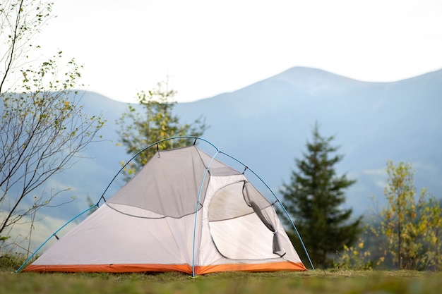 Lege wandelaarstent die op camping staat met uitzicht op majestueuze hoge bergtoppen in de verte.