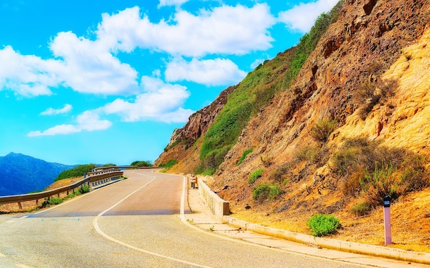 Lege weg zonder auto's bij Capo Pecora op het eiland Sardinië in de zomer van Italië. Vervoer rijden op de snelweg van Europa. Vakantie op snelweg. provincie Cagliari. Bergen op de achtergrond. Gemengde media.