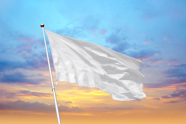 Lege witte vlag op paal zwaaiend in de wind op de achtergrond van zonsonderganghemel