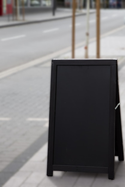 Lege zwarte reclamestandaard/sandwichbord buiten geplaatst