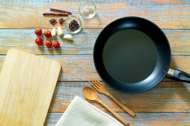 lege zwarte ronde gietijzeren pan met handvat houten snijplank en mes op een grijze tafel