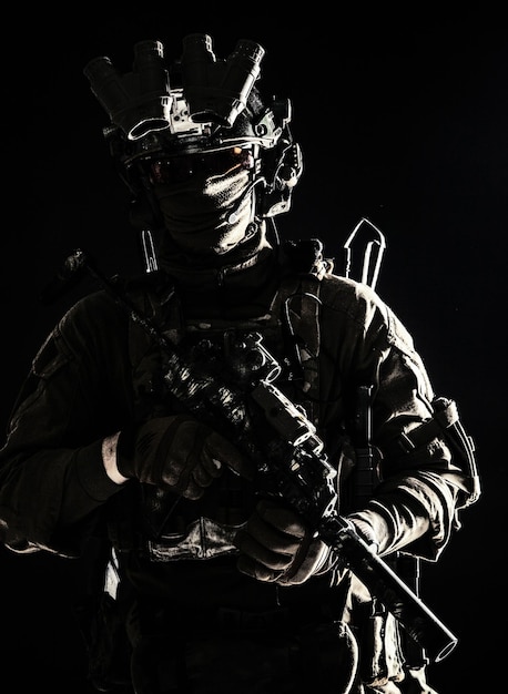 Foto leger elite troepen militair contraterroristische teamlid dragen masker en bril uitgerust nachtzicht apparaat radio hoofdtelefoon gemonteerd op gevechtshelm gewapend machinepistool staande in duisternis