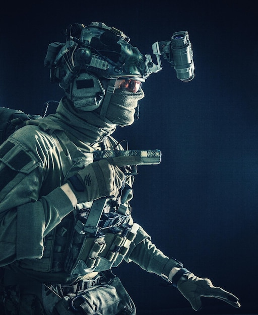 Foto leger speciale operaties soldaat veiligheidsdienst vechter commando schutter uitgerust moderne munitie dragen gevechtshelm masker en bril zorgvuldig sluipend in het donker met pistool in de hand