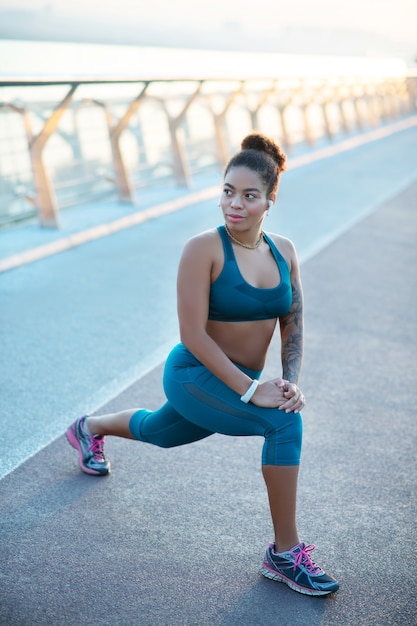 Leggings and top. Dark-skinned appealing woman wearing leggings and top stretching after run