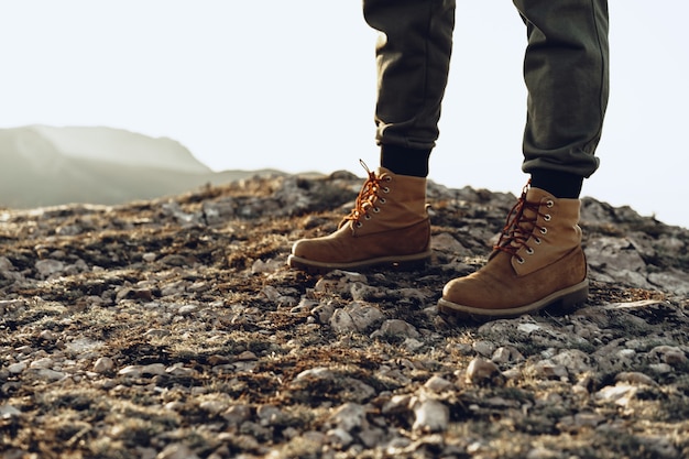 Legs of a backpacker in hiking boots standing on the top of the mountain 