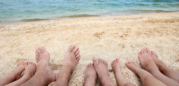 海の背景の近くの砂の上の美しい家族全員の足