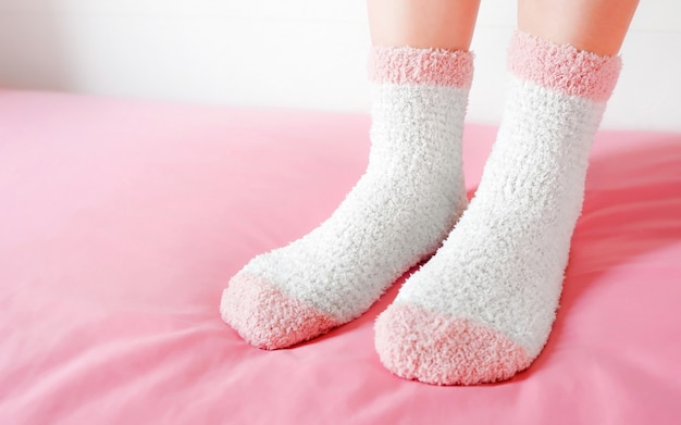 Legs of a beautiful women are wearing warm Socks on bedroom. Fashion pink Socks in cozy.