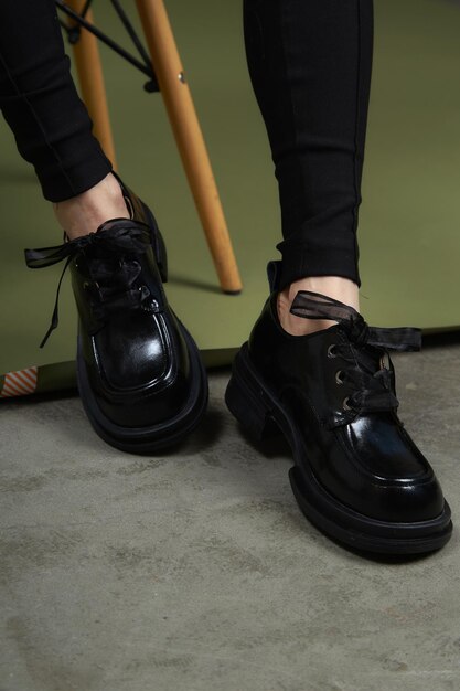 Legs in black boots on green background Casual lifestyle photo Fashion shoes made of ecoleather