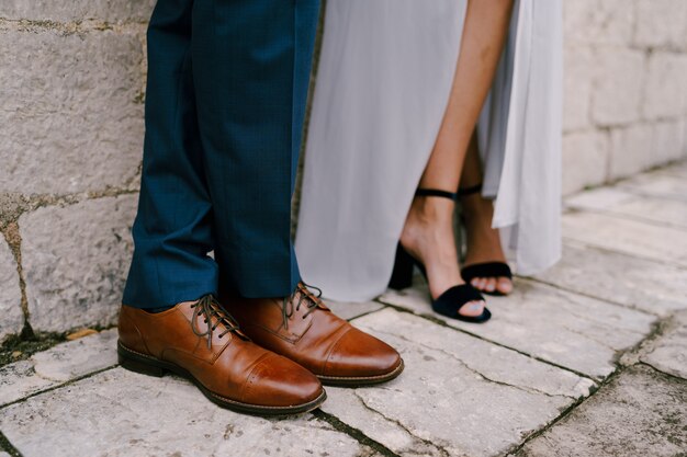 Gambe della sposa e dello sposo in primo piano delle scarpe da sposa