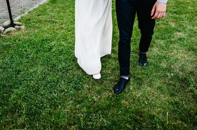 The legs of the bridegroom on the grass. Bride and groom. Newlyweds.