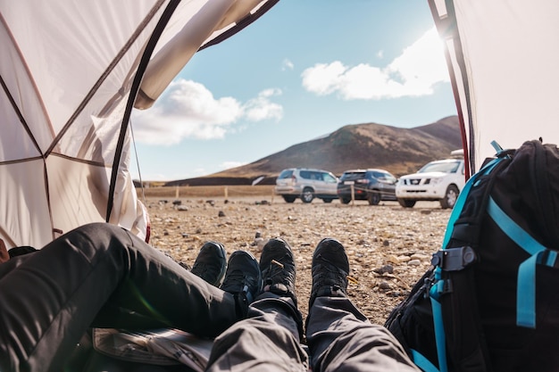 Legs of couple traveler relaxing inside a tent in wilderness on campground in summer