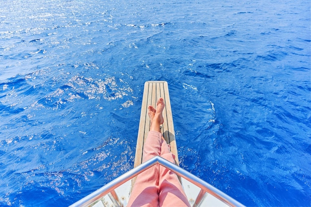 Legs of free carefree traveler girl while enjoying relaxing and calm private vacay on a boat in the turquoise sea