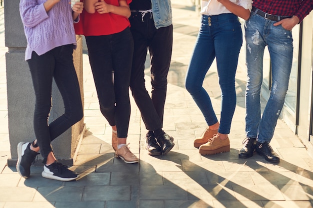 Gambe di un gruppo di giovani casuali. moda giovanile. raccolto di diversi studenti informali in fila all'aperto sullo sfondo urbano