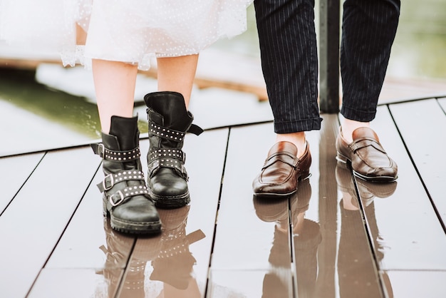 Legs of the just married on the background of the wharf.The bride and groom stand and pose in boots on the pier.