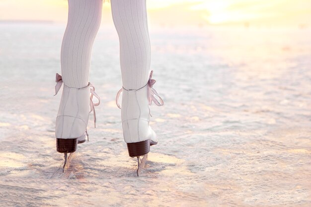 Legs of little girl skating on ice in evening sunset light