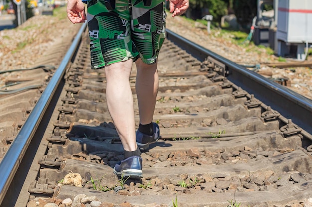 The legs of a lonely man walking on rails on a railway line