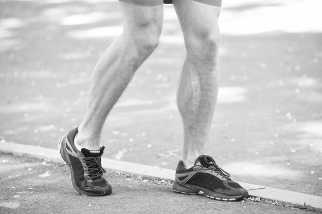 Gambe dell'atleta maschio corridore jogging parco marciapiede stile di vita attivo allenamento cardio scarpe sportive malattia vascolare vene varicose problemi vita attiva prevenire il concetto di varicose malattia causata dalla corsa