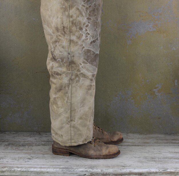 Foto le gambe di un uomo con vecchi pantaloni e vecchie scarpe