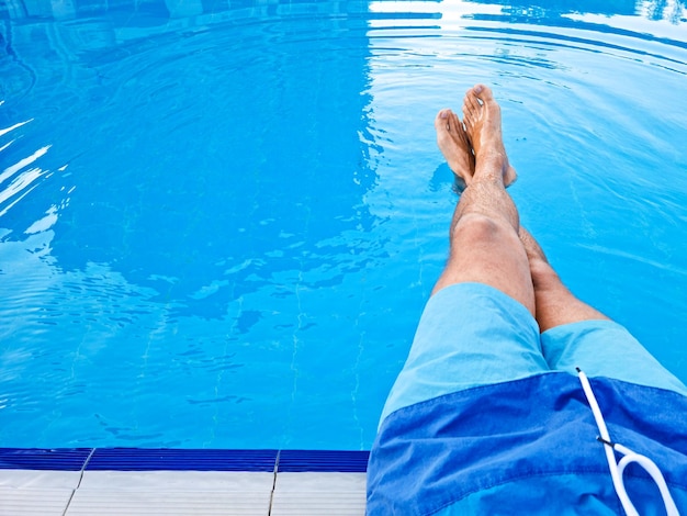 Legs of a man in the pool Relax concept Template Copy space for text