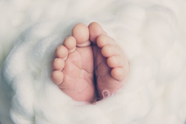 写真 白いケーブルニットに包まれた脚の生まれたばかりの赤ちゃん