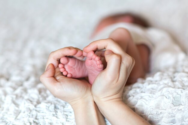 Legs of a newborn in the hands of mother