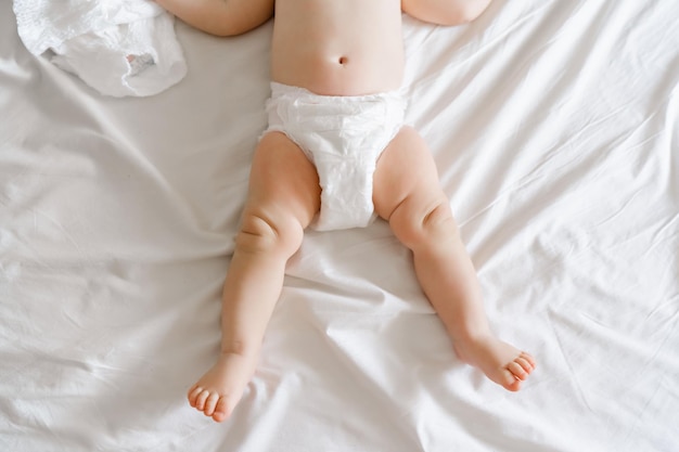 사진 집에서 침대에 누워 기저귀에 6 개월 된 아기의 다리 고품질 사진