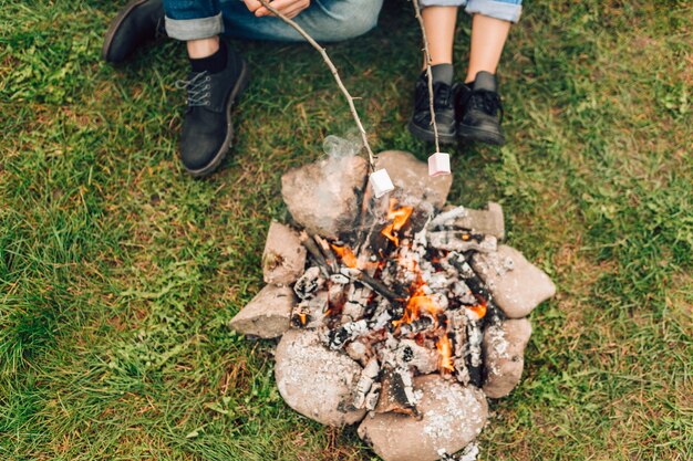 Фото Ноги пары возле огня, жарят зефир.