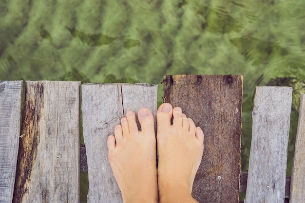 Gambe sul vecchio molo sullo sfondo del mare