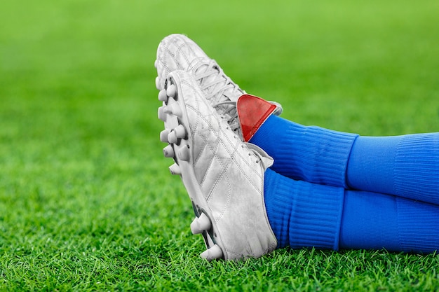 Photo legs of a player in football on a green lawn