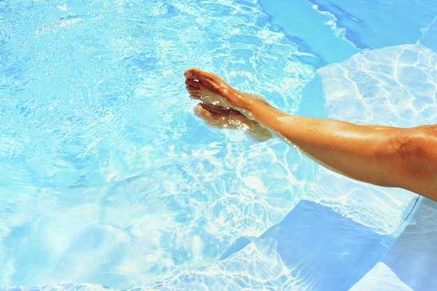 Legs in the pool with clean water in hot sunny day Summer background for traveling and vacation Holiday idyllic