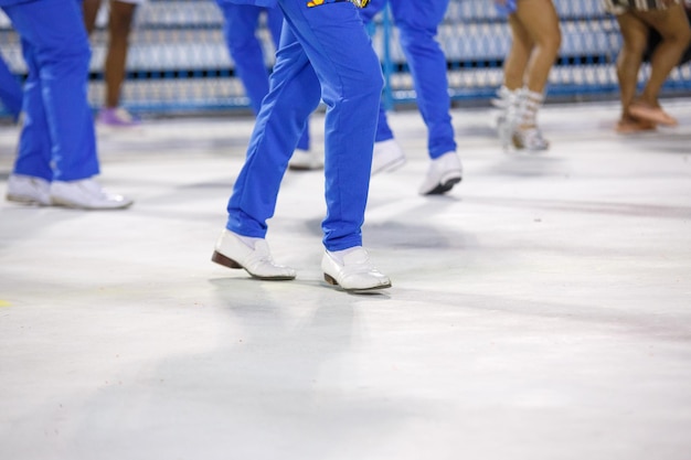Ноги самбиста, танцующего в синих штанах и белых туфлях на самбодроме да маркиз де сапукай в Рио-де-Жанейро