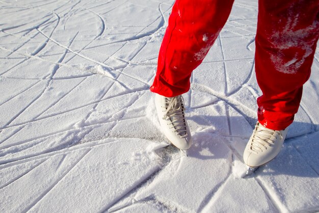 Legs of skater on winter ice rink in outdoors