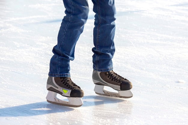 アイススケートリンクでスケートをしている男の足。趣味とレジャー。ウィンタースポーツ