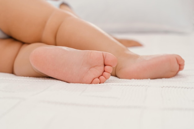 Legs of a sleeping baby on a white blanket, selective focus